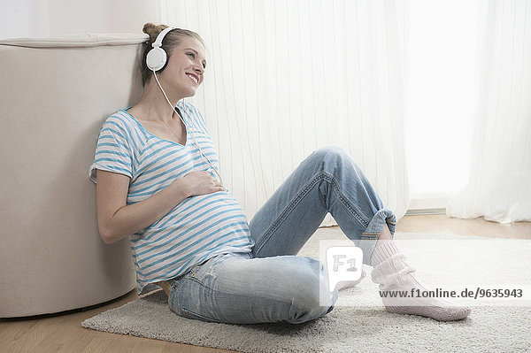 Young pregnant woman headphones listening music