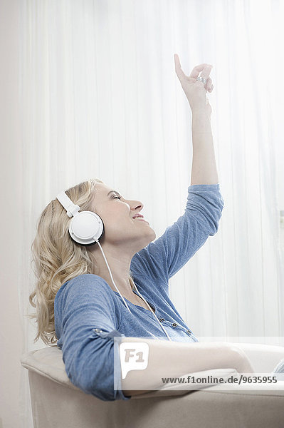 Young blond woman sitting chair listening music