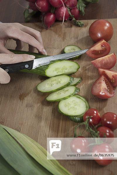 Close up woman cutting cucumber preparing salad