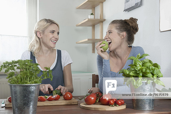 Two young women talking kitchen preparing salad