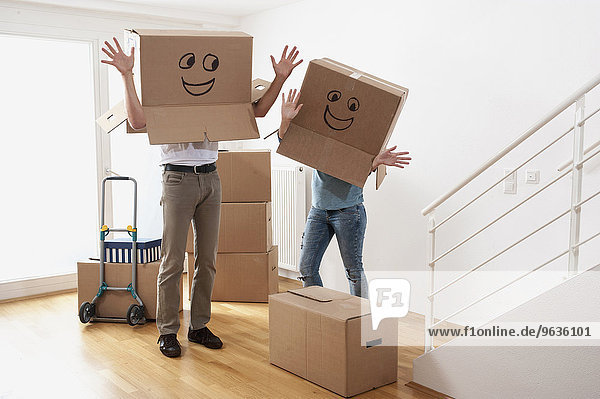 Couple wearing happy face moving boxes over heads and dancing