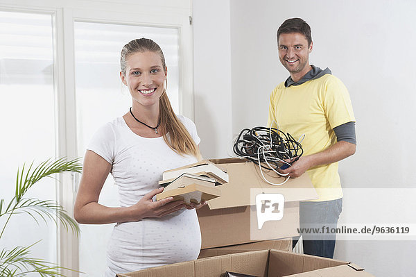 Pregnant woman packing with her husband while moving to new apartment