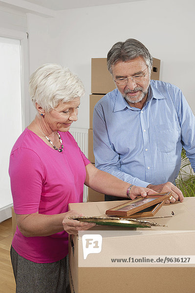 Senior couple looking at picture frames in new apartment