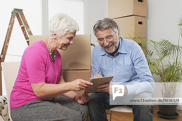 Senior couple using a digital tablet in new apartment