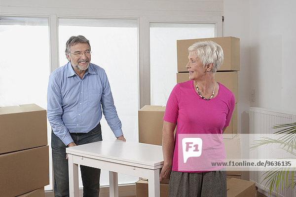 Senior couple moving a table in new apartment