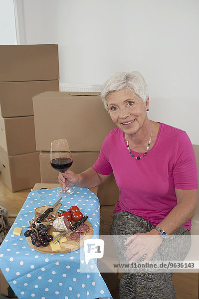 Senior woman moving into new home celebrating with wine