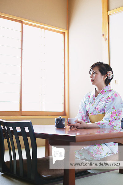 Young Japanese woman in a yukata drinking tea