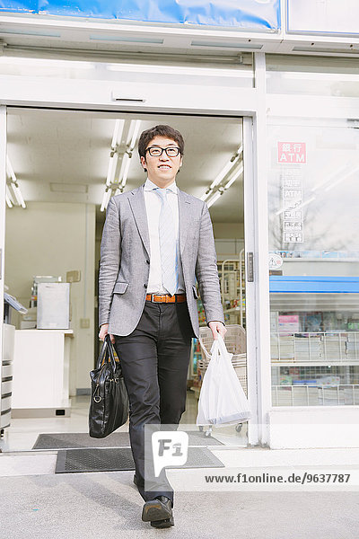 Japanese businessman walking out from a convenience store