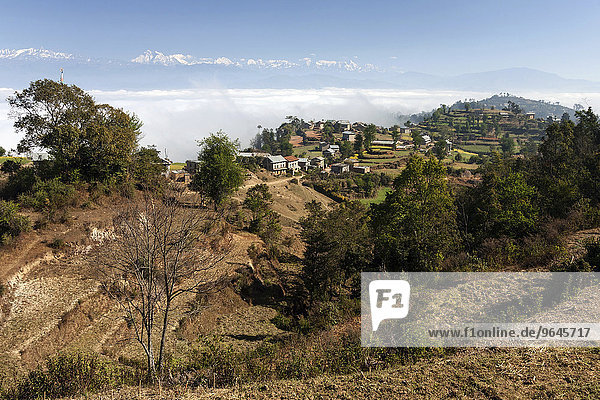 Ausblick auf Landschaft  ländliche Häuser  Terrassenfelder und Berge des Himalaya  Nebel liegt im Tal  bei Dhulikel  Nepal  Asien