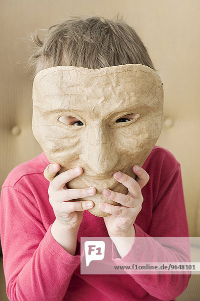 Mädchen versteckt Gesicht hinter Maske