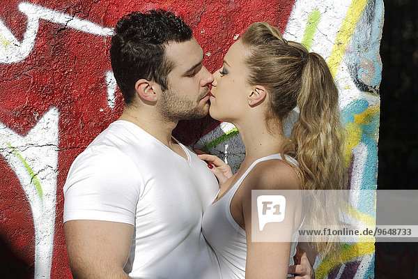 Young couple kissing in ruined building covered in graffiti