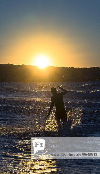 Young man  silhouette  jumping in the water at sunset  sunset by the sea  Haute-Corse  Corsica  France  Europe