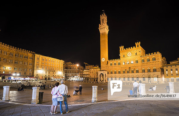 Tourists at the Palazzo Pubblico with illuminated Mangia Tower and chapel  night  Piazza Il Campo  Siena  Tuscany  Italy  Europe