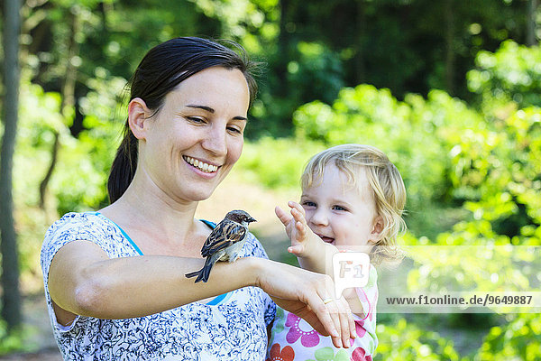 Junge Mutter und Kleinkind mit Spatz auf dem Arm  Lainzer Tiergarten  Wien  Österreich  Europa