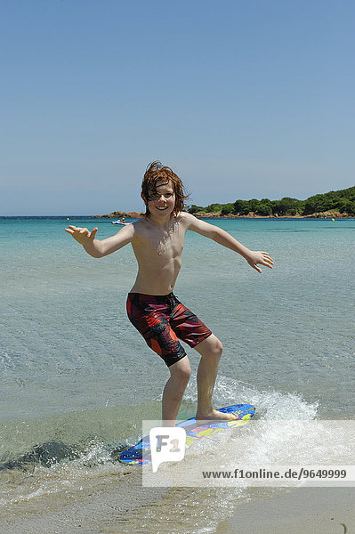 Junge surft mit seinem Boogie Board  Beach Board oder Skimboard am Strand  Bucht von Rondinara  Südostküste  Korsika  Frankreich  Europa