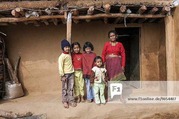 Alte nepalesische Frau und vier Kinder vor einem typischen nepalesischen ländlichen Haus  bei Bandipur  Nepal  Asien