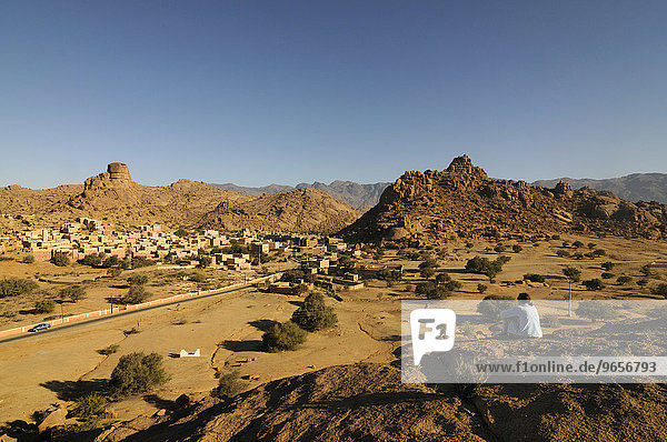 Touristin entspannt sich vor einem malerischen Bergdorf bei Tafraoute  Südmarokko  Marokko  Afrika