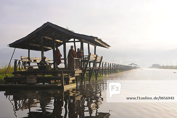 Monks on a jetty in the early morning light  Inle Lake  Bagan  Myanmar  Burma  Southeast Asia  Asia
