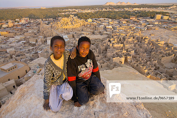 Two smiling boys in front of the ruined city of Shali  Siwa  Egypt  Africa