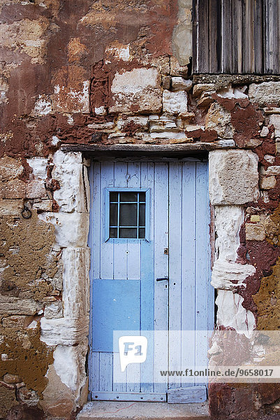 Alaue Tür in alter roter Steinmauer  Roussillon  Provence  Südfrankreich