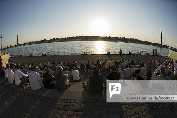 People enjoying the evening sun on the steps between the Burgplatz Square and the promenade on the banks of the Rhine River  historic city centre  Duesseldorf  North Rhine-Westphalia  Germany  Europe