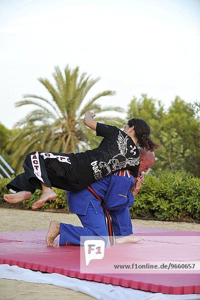 Eine Frau und ein Mann beim Kampfsport-Training in einem Park