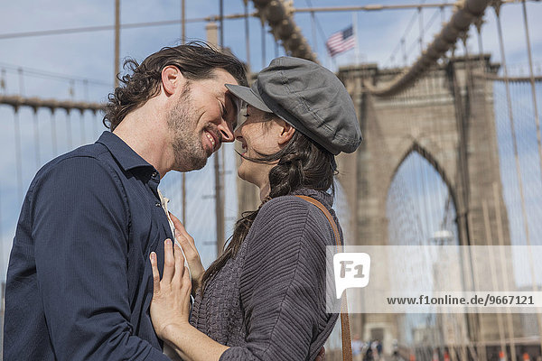Happy couple kissing on Brooklyn Bridge