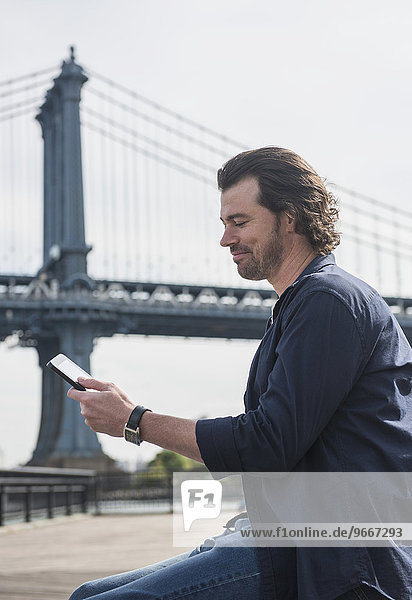 Man using tablet pc  Manhattan Bridge in background