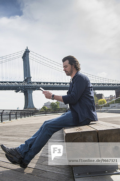 Man using tablet pc  Manhattan Bridge in background