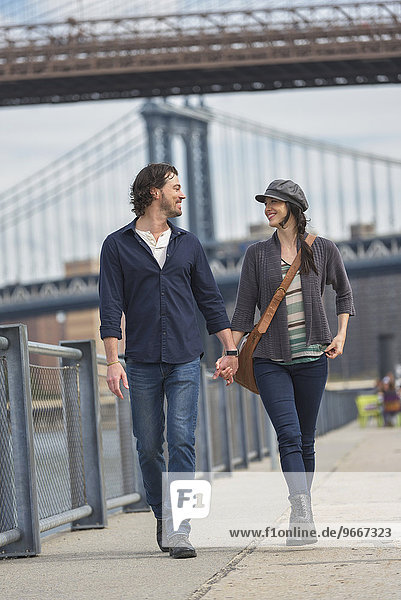 Couple walking on promenade  Brooklyn Bridge in background
