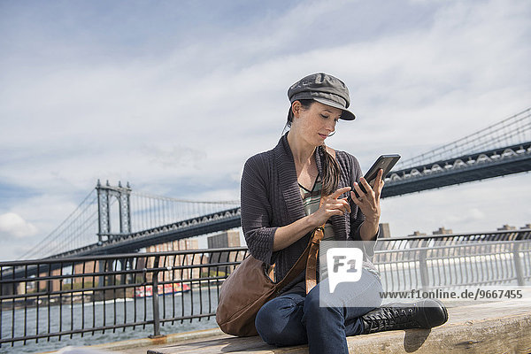 Woman using tablet pc  Manhattan Bridge in background