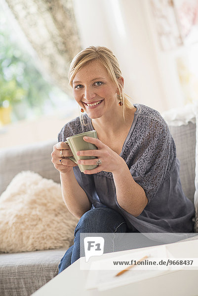 Woman sitting on sofa and drinking coffee