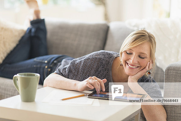 Woman lying down on sofa with tablet pc