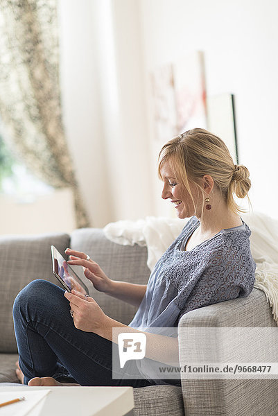 Smiling woman sitting on sofa with tablet pc