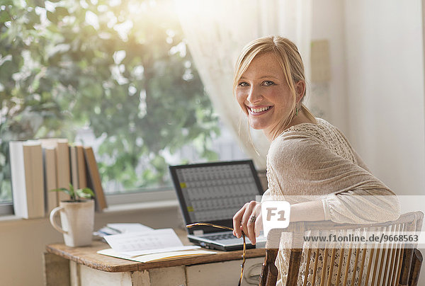 Smiling woman sitting at desk and looking over shoulder