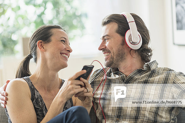 Cheerful couple listening to music at home