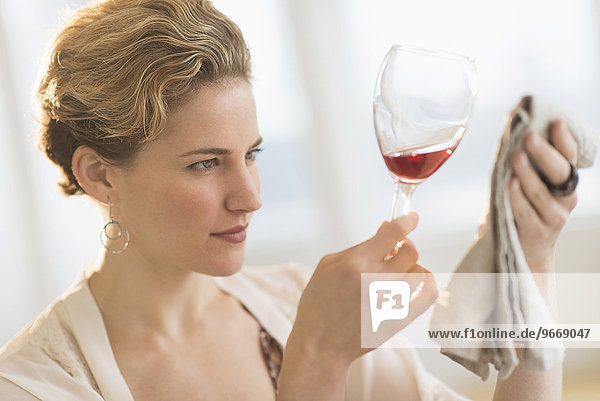 Young woman looking closely at red wine