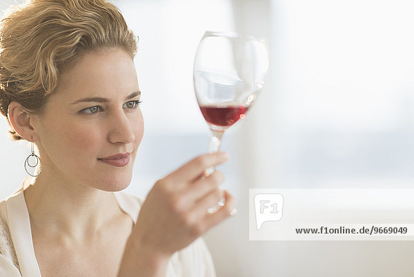 Young woman examining red wine