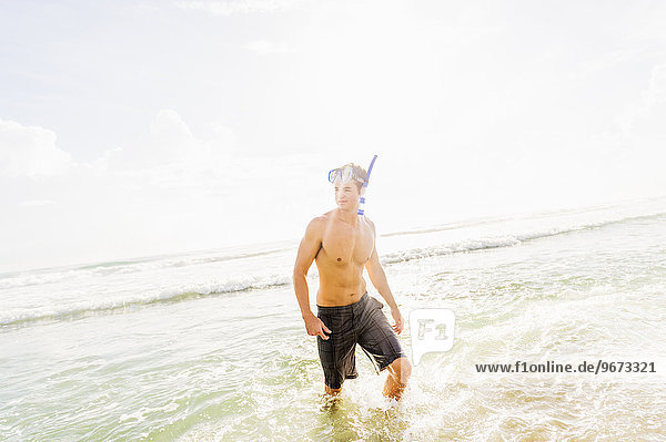 Portrait of young man walking in surf wearing scuba mask and snorkel