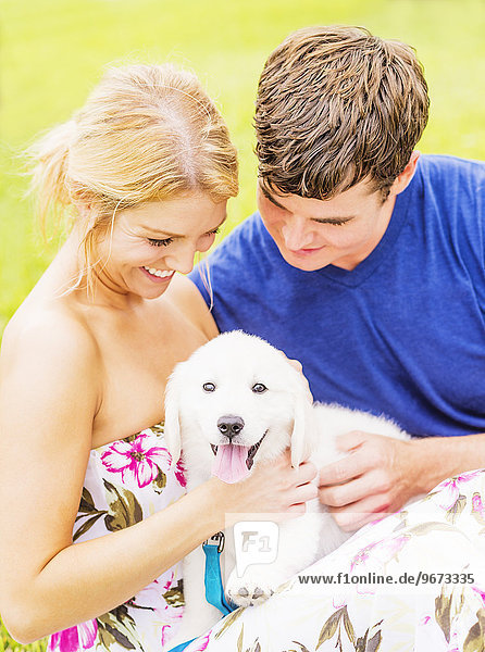 Portrait of young couple caressing white puppy
