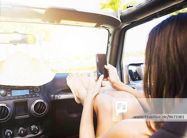sitzend junge Frau junge Frauen benutzen Auto Smartphone Armaturenbrett
