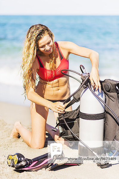 junge Frau junge Frauen Zusammenhalt kniend Strand Gerät Sand Taucher Tauchausrüstung