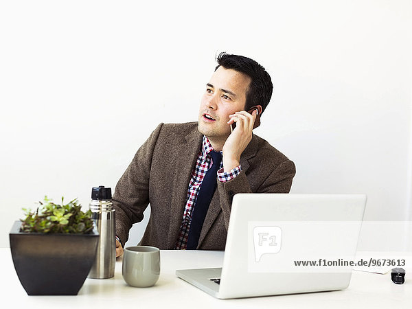 Businessman sitting in office and making phone call
