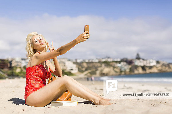 Blond woman taking selfie on beach