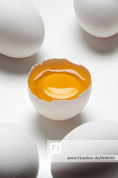 Fünf Eier auf weissem Untergrund  eins davon aufgeschlagen
