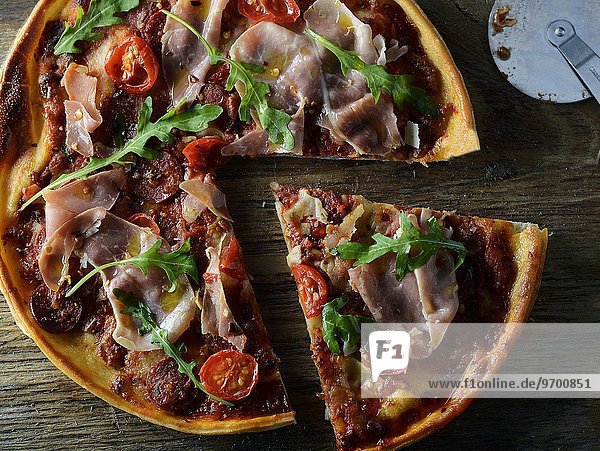 Pizza mit Prosciutto  Tomaten und Rucola  angeschnitten