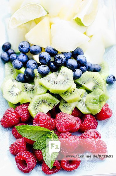 Frisches Obst (Blaubeeren,  Kiwi,  Himbeeren) mit Minzeblättchen