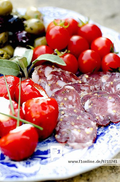 Antipastiteller mit Salamischeiben  Kirschtomaten  Kirschpaprika mit Ricottafüllung und Oliven