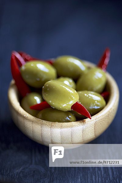 Grüne Oliven  gefüllt mit Chilischoten  im Holzschälchen