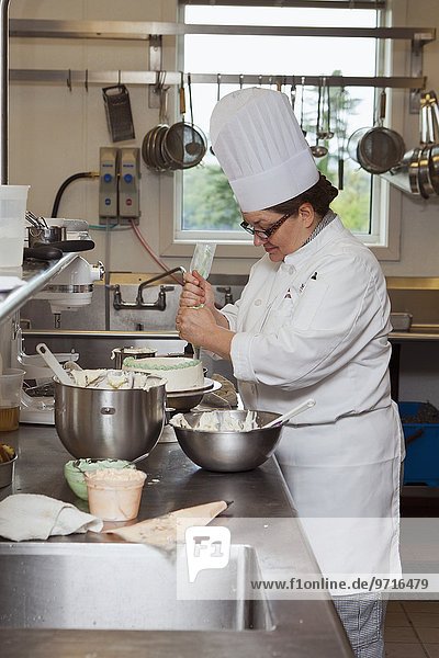 A chef decorating a cake with icing